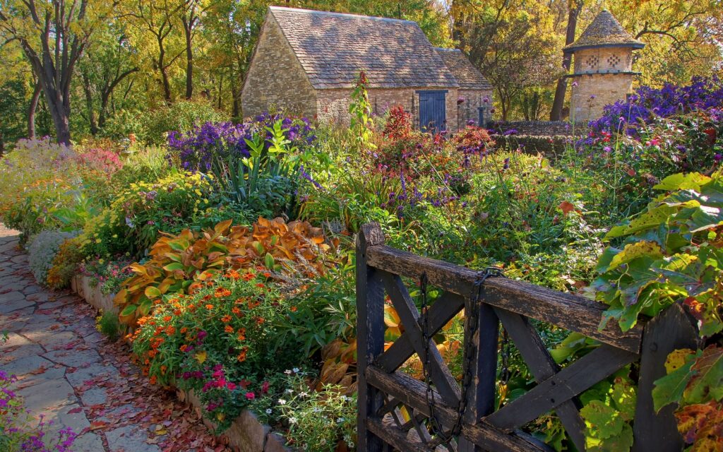 Michigan State University Salary Cuts. Fall scene with stone cottage, walkway and fence